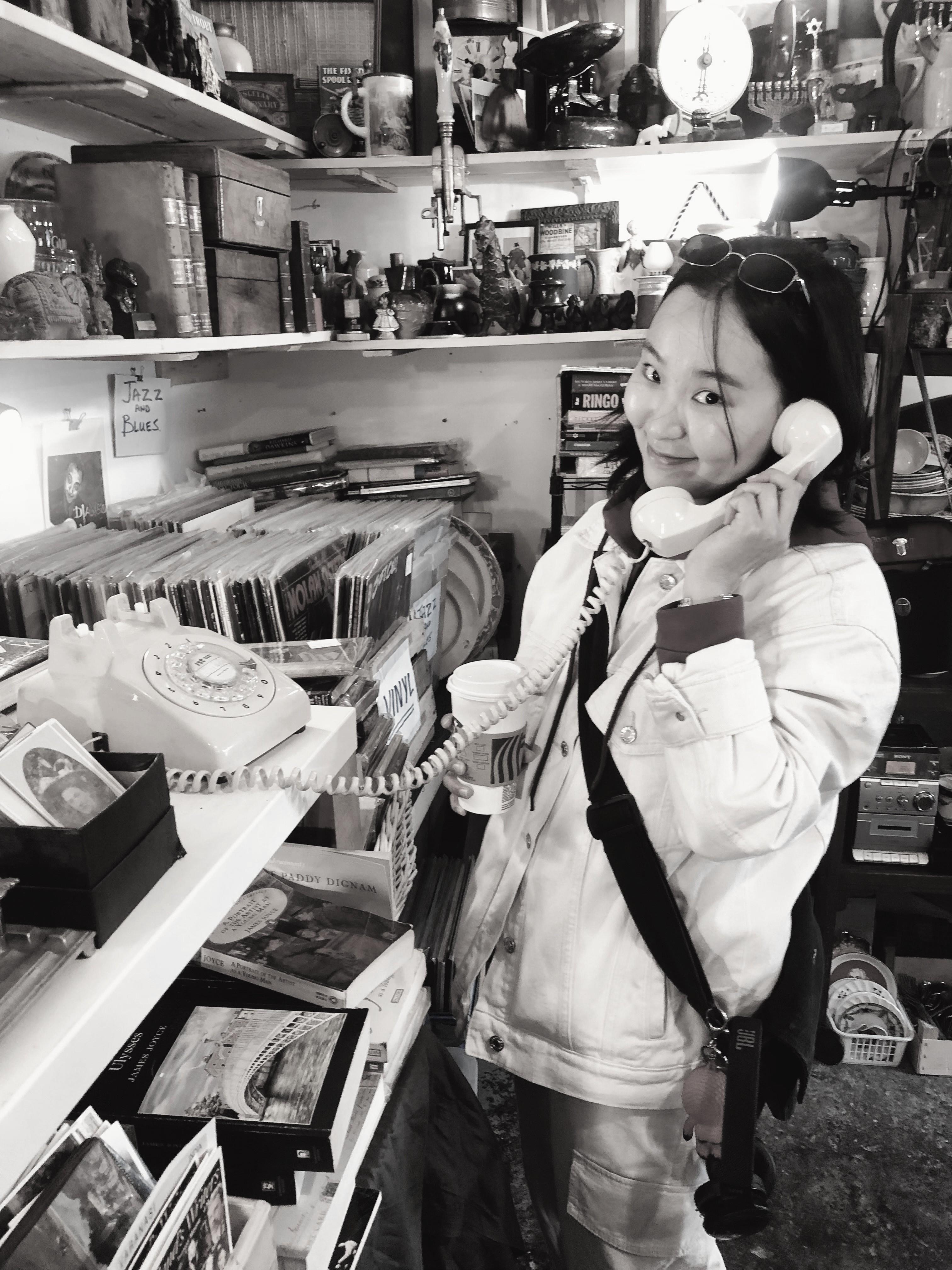 Nami holding two vintage telephone receivers in a record shop